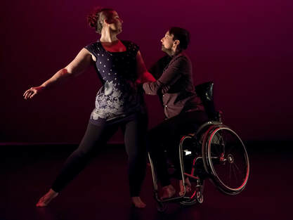 Lindsay and Danielle dance a duet. Danielle tilts up on one wheel, and shares weight with Lindsay. They smile at each other